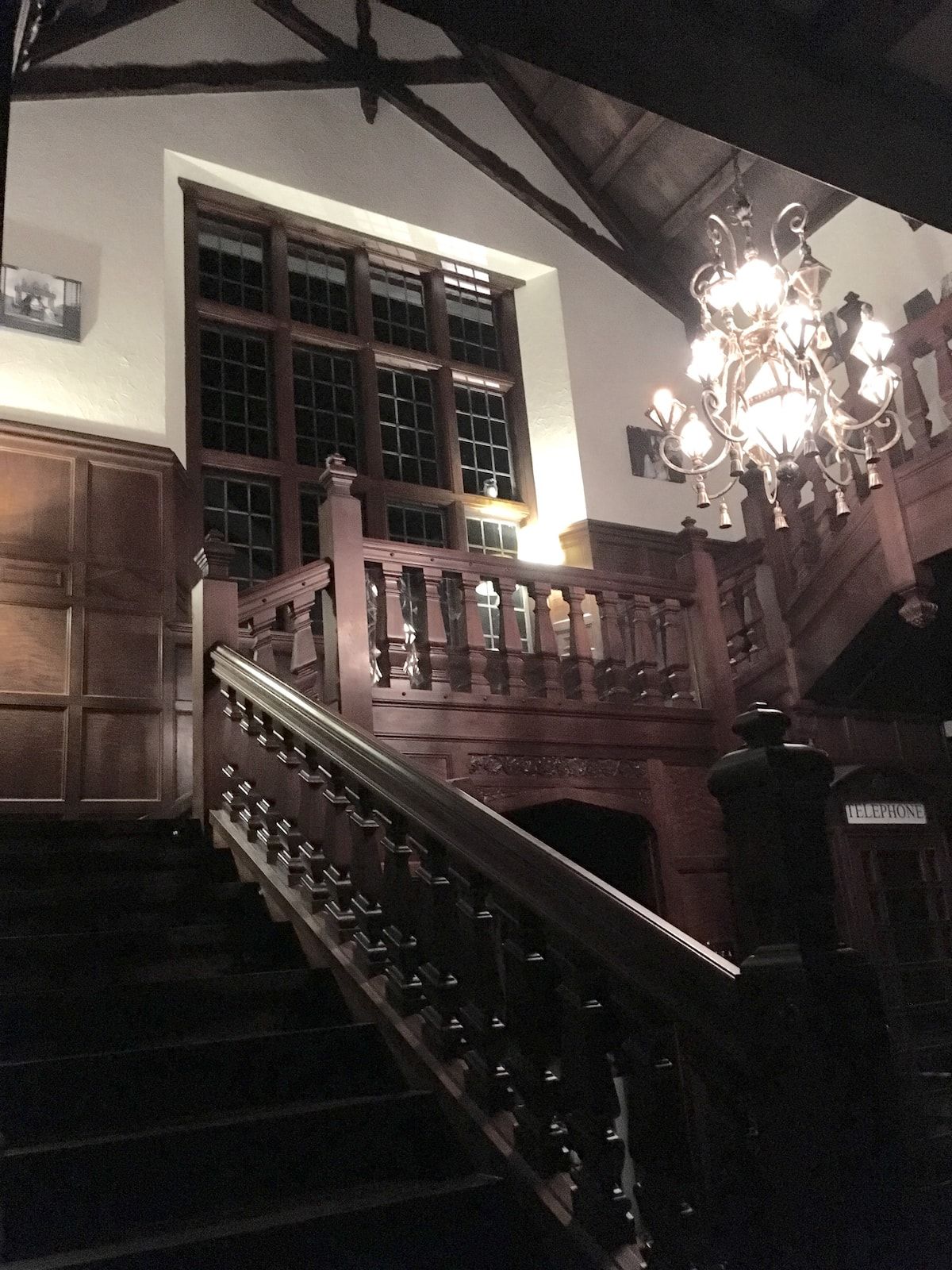 Grand staircase and foyer with dark wood paneling and vintage telephone booth