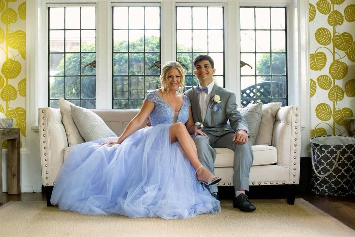Formally dressed couple seated on elegant sofa in mansion sunroom with leaded glass windows