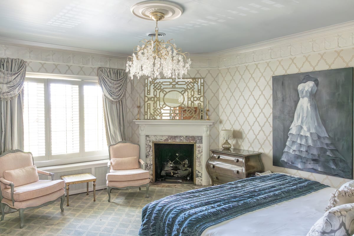 Bedroom with fireplace, crystal chandelier, and wallpaper