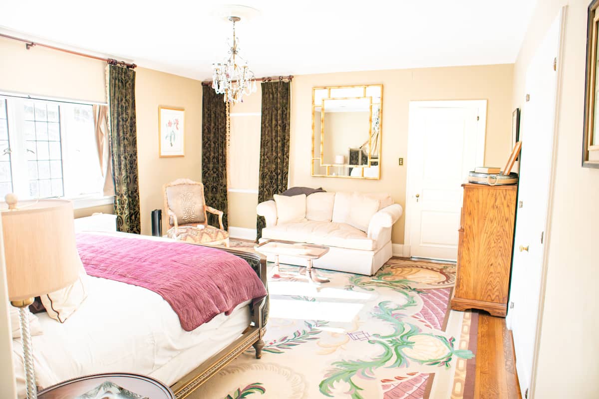 Elegant bedroom with pink bed, crystal chandelier, and loveseat