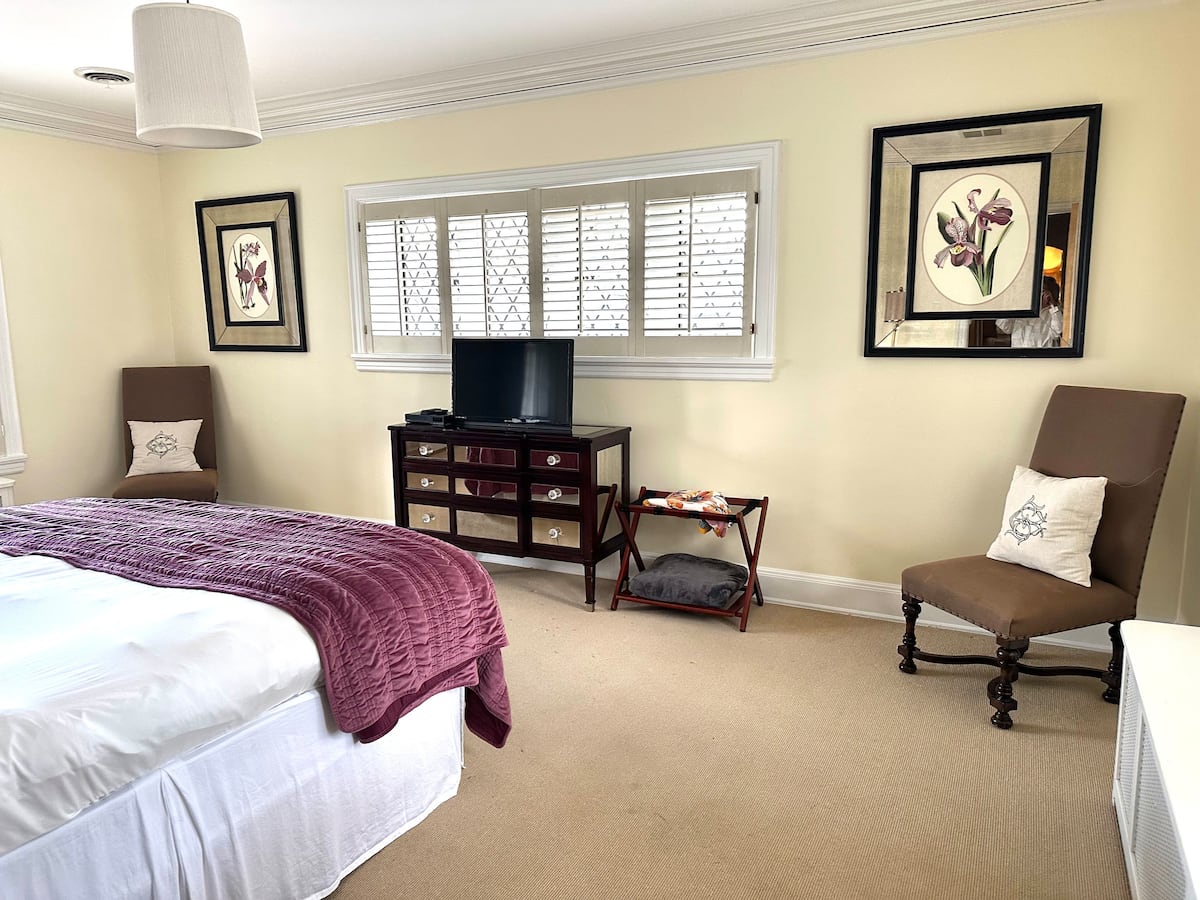 Guest bedroom with purple throw and botanical art