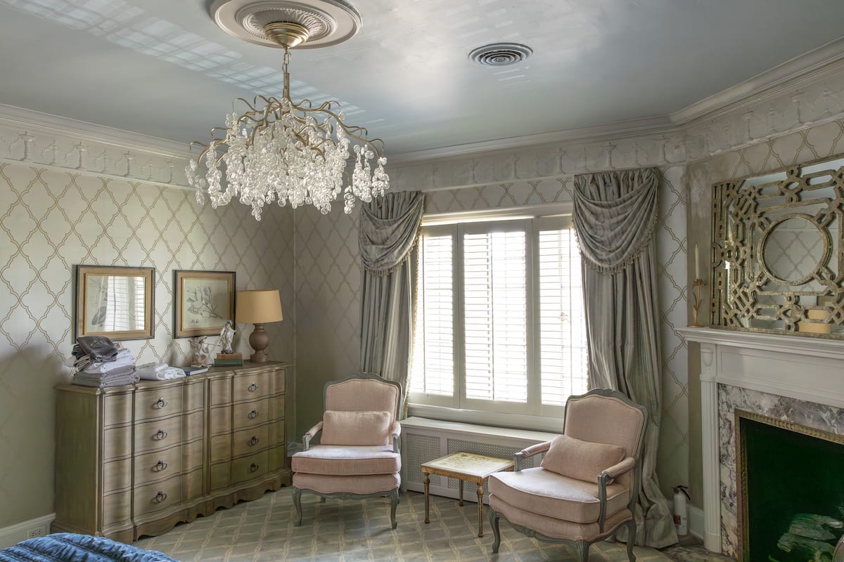 Elegant bedroom with trellis wallpaper and blue velvet throw
