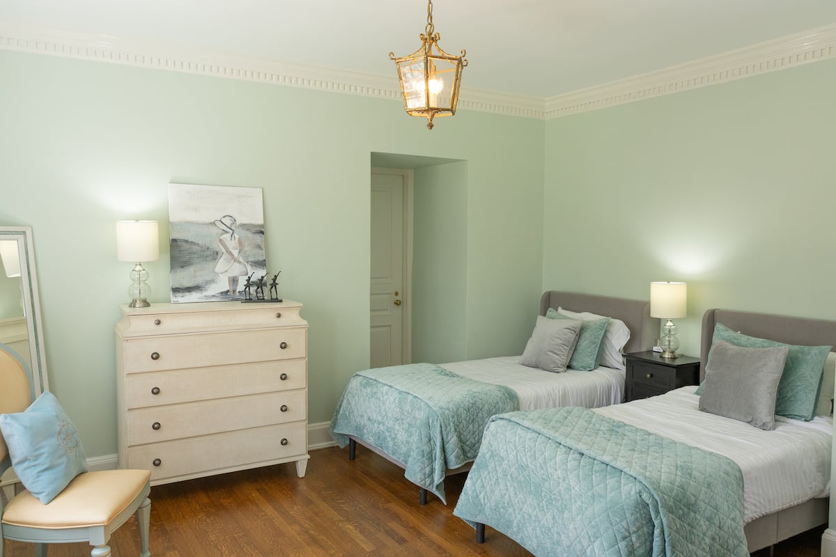 Twin beds room in mint green with gold pendant light