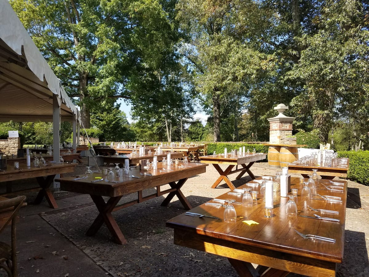 Outdoor rustic dining setup with wooden tables and tent canopy