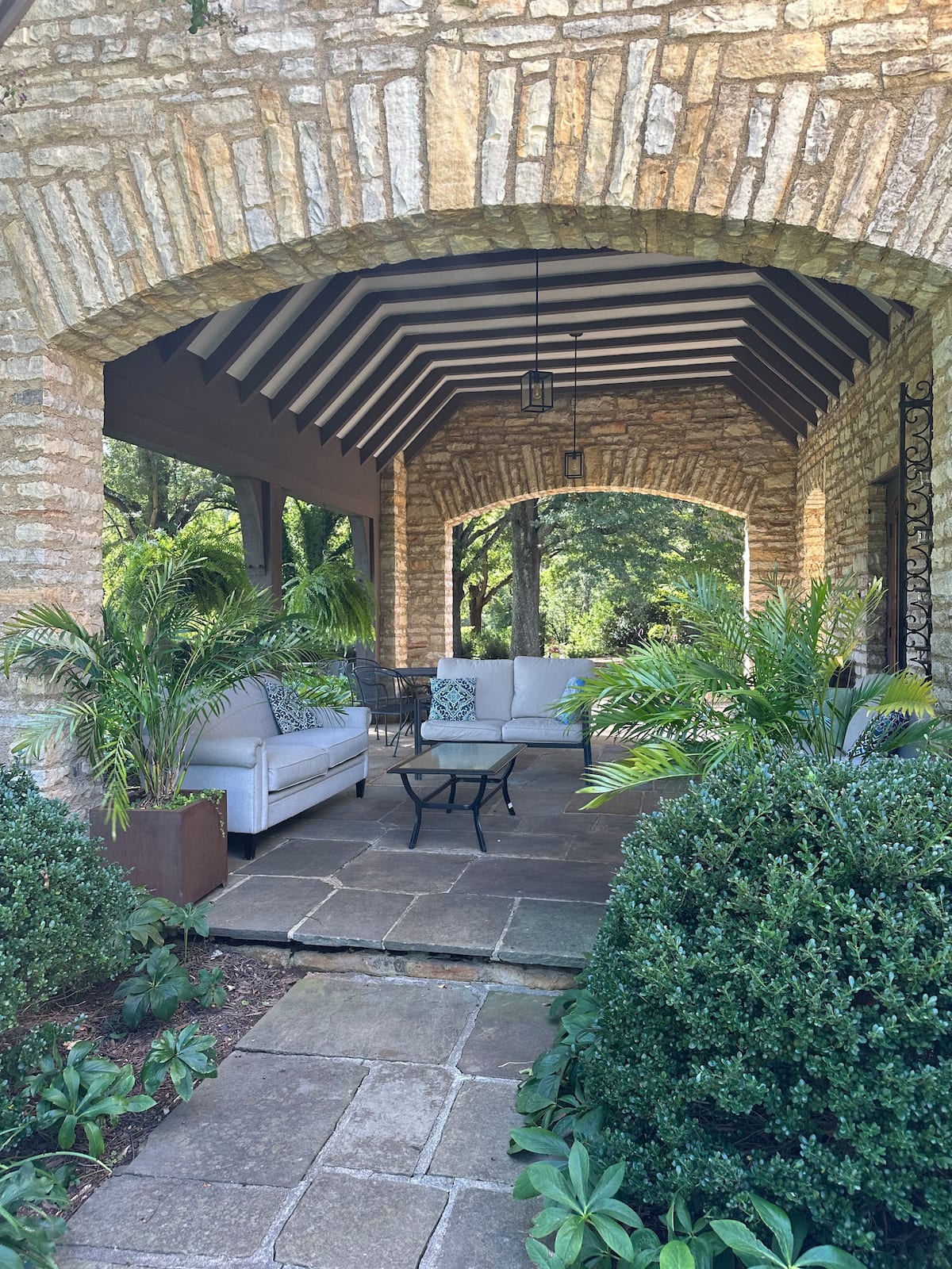 Covered stone patio with outdoor sofas and climbing plants
