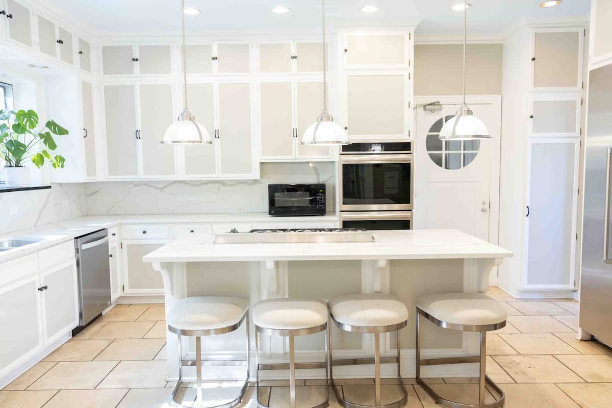 White kitchen wide view with bar stools and gas cooktop