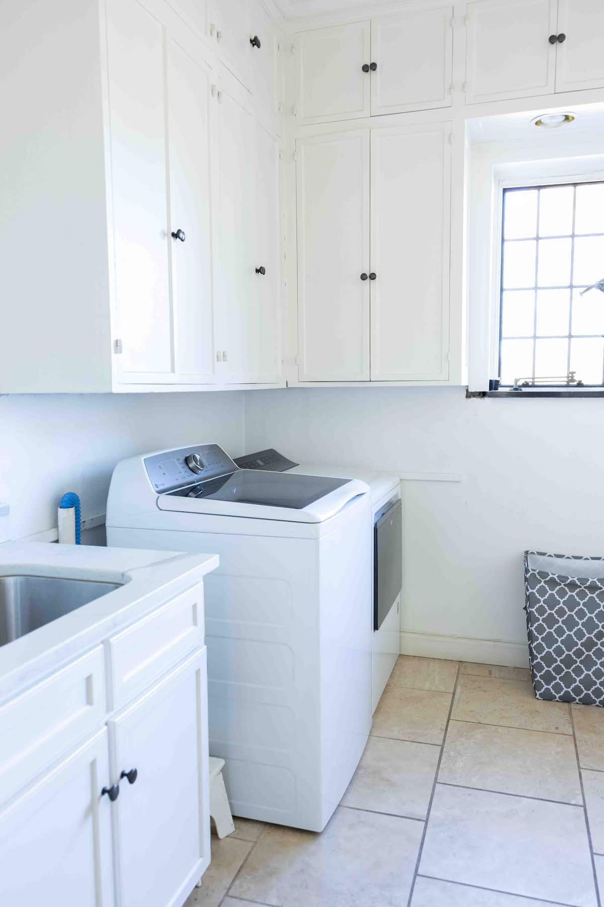 White laundry room with washer dryer and utility cabinets
