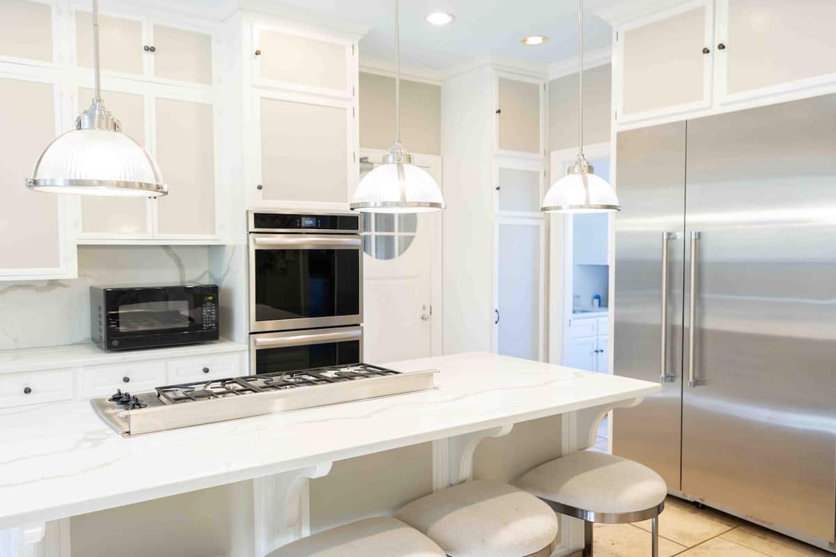 White modern kitchen with marble island and stainless appliances