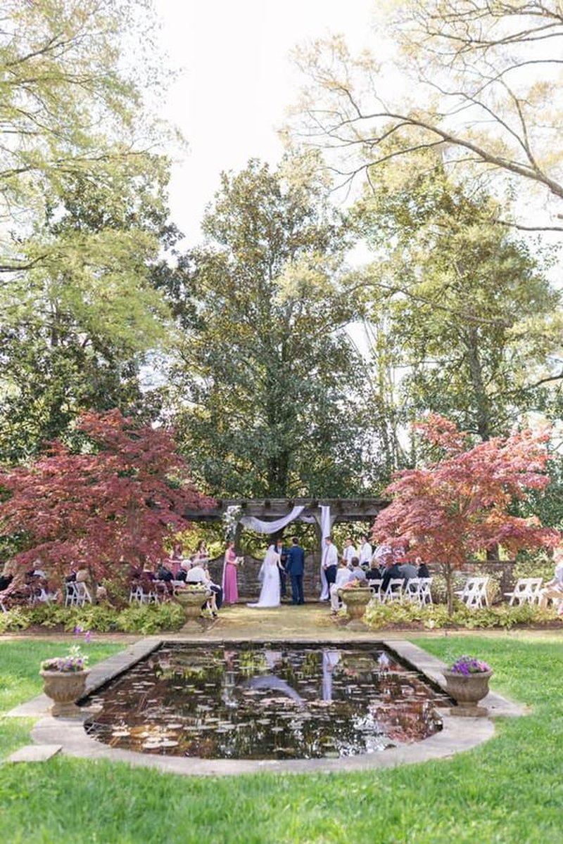 Outdoor wedding ceremony at garden arbor with reflecting pond, Japanese maples, seated guests