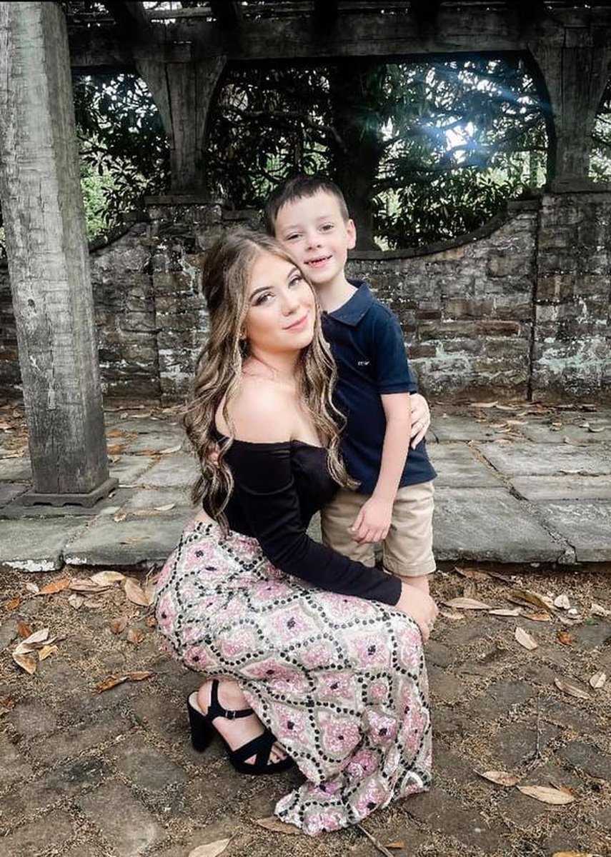 Young woman and small boy posing together under stone pergola on grounds
