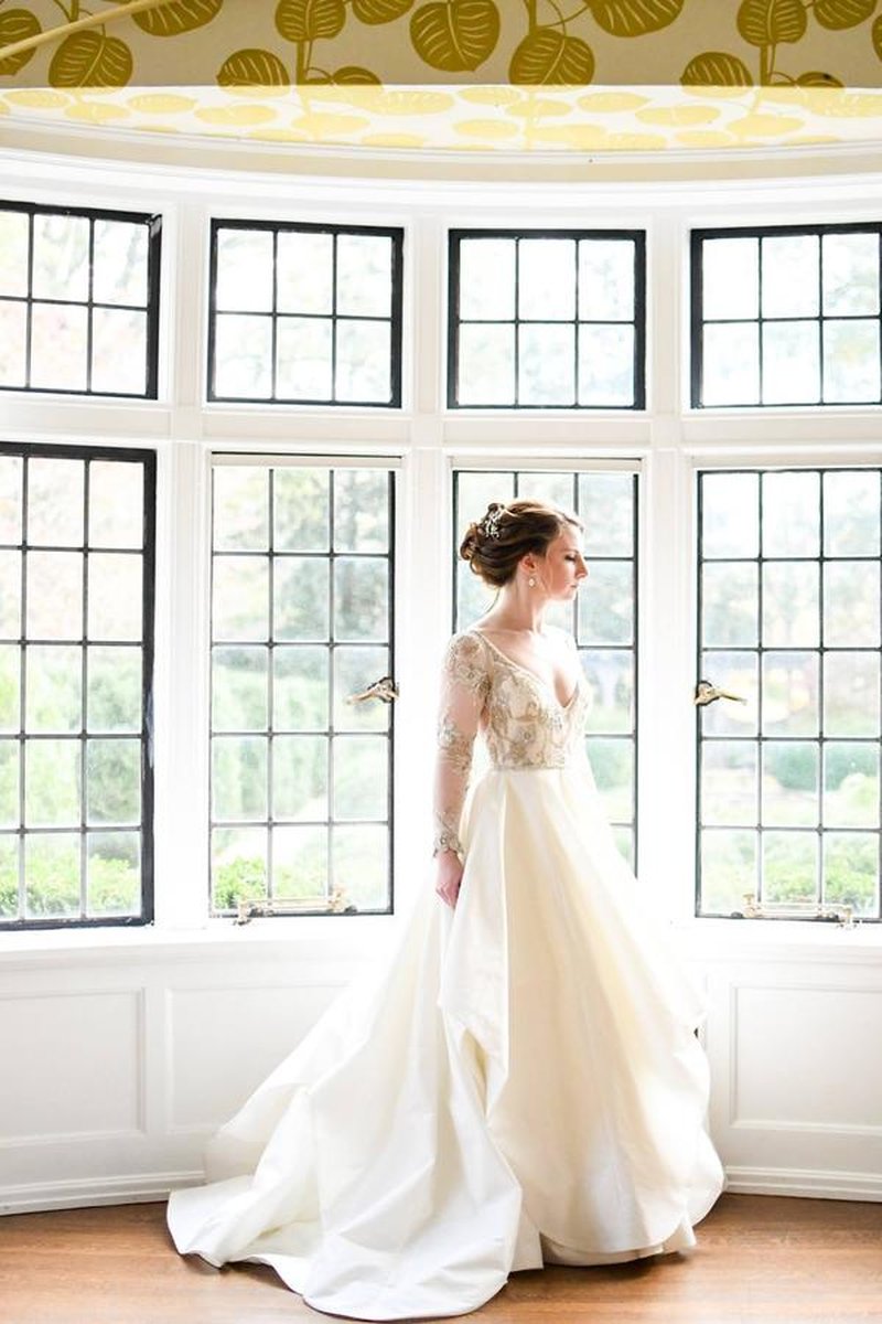 Bride standing in bay window alcove — near-identical to previous shot