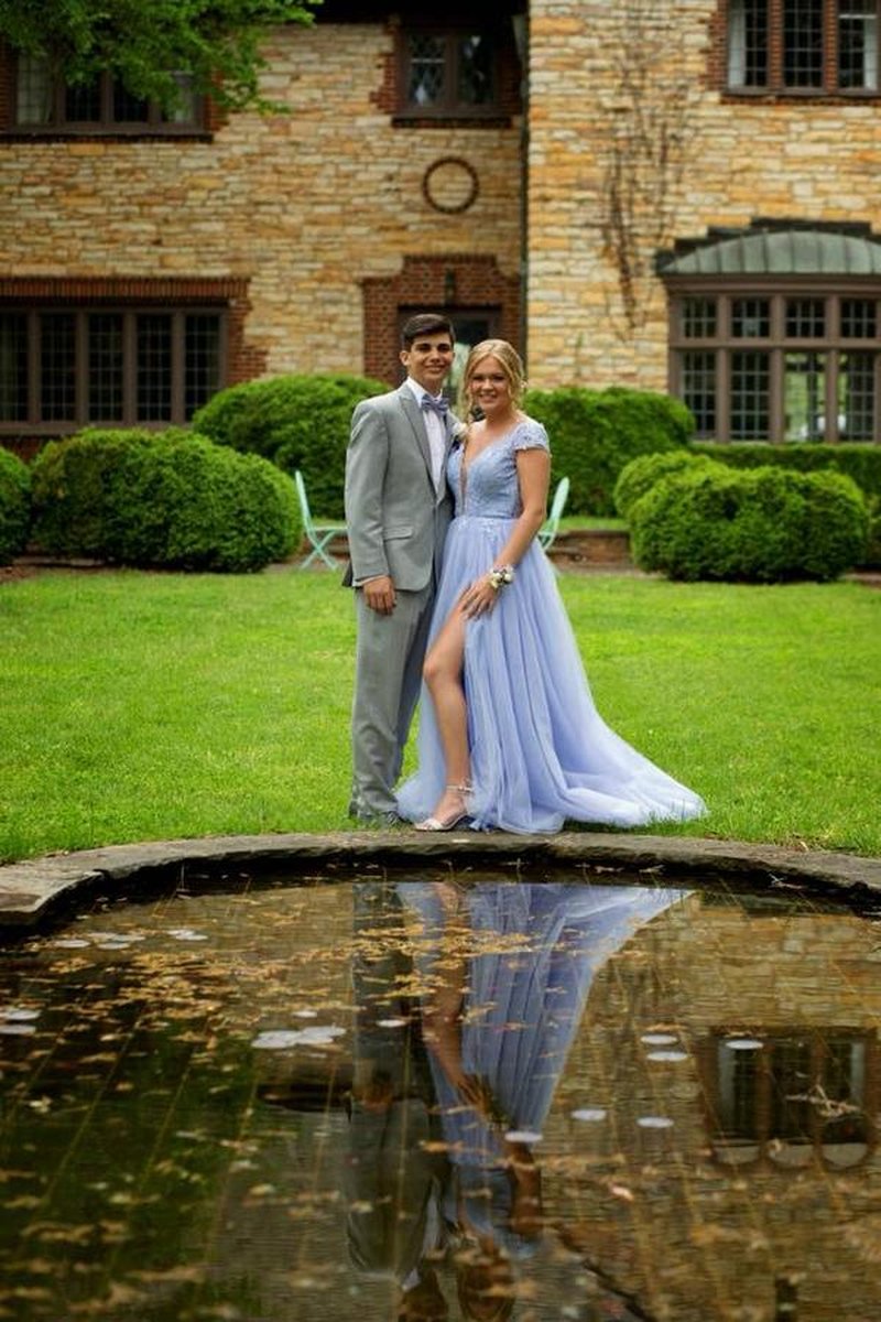 Couple posing by reflecting pond with stone mansion facade in background