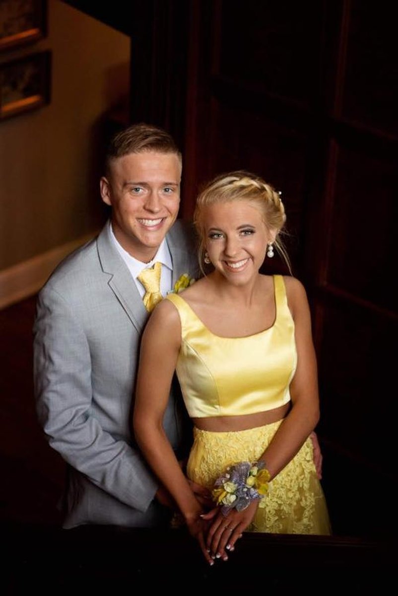 Formally dressed couple posing inside dark wood-paneled mansion interior