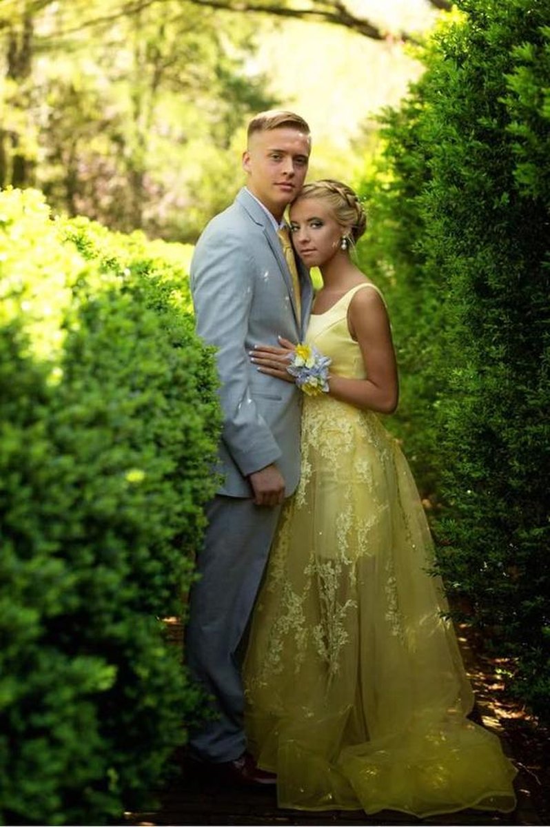 Couple embracing between tall manicured boxwood hedges on estate grounds