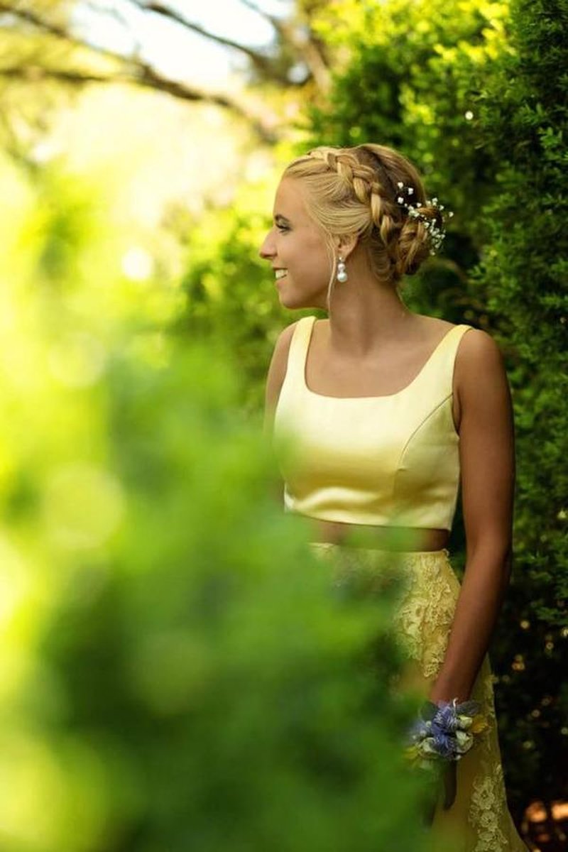 Portrait of young woman in yellow two-piece dress with braided updo and baby's breath