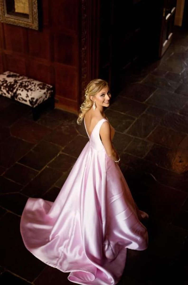 Young woman in pink ballgown twirling on slate floor inside wood-paneled mansion foyer