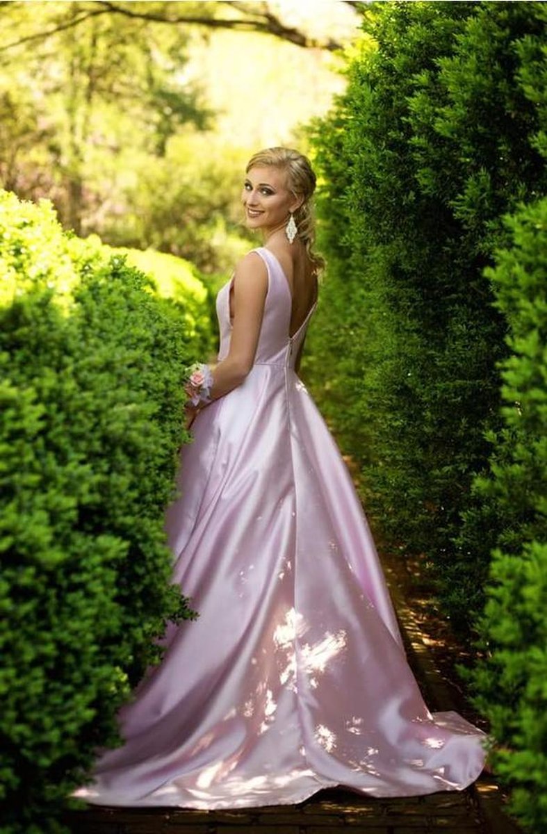 Bride in lavender/pink satin gown walking through lush garden hedge pathway