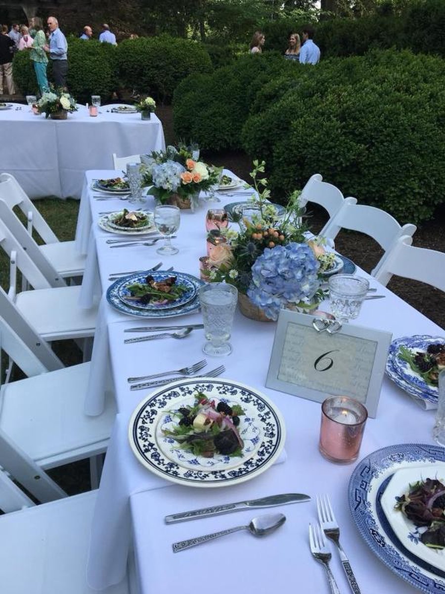 Close-up of outdoor reception table with blue-and-white china, hydrangea centerpieces, candles