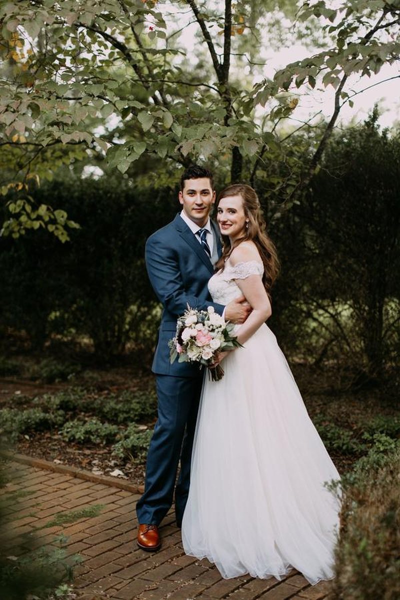 Bride and groom portrait on brick garden path with lush greenery