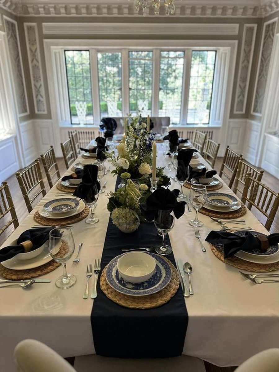 Elegant formal dining table in ornate mansion room with blue willow china, navy runner, gold chairs