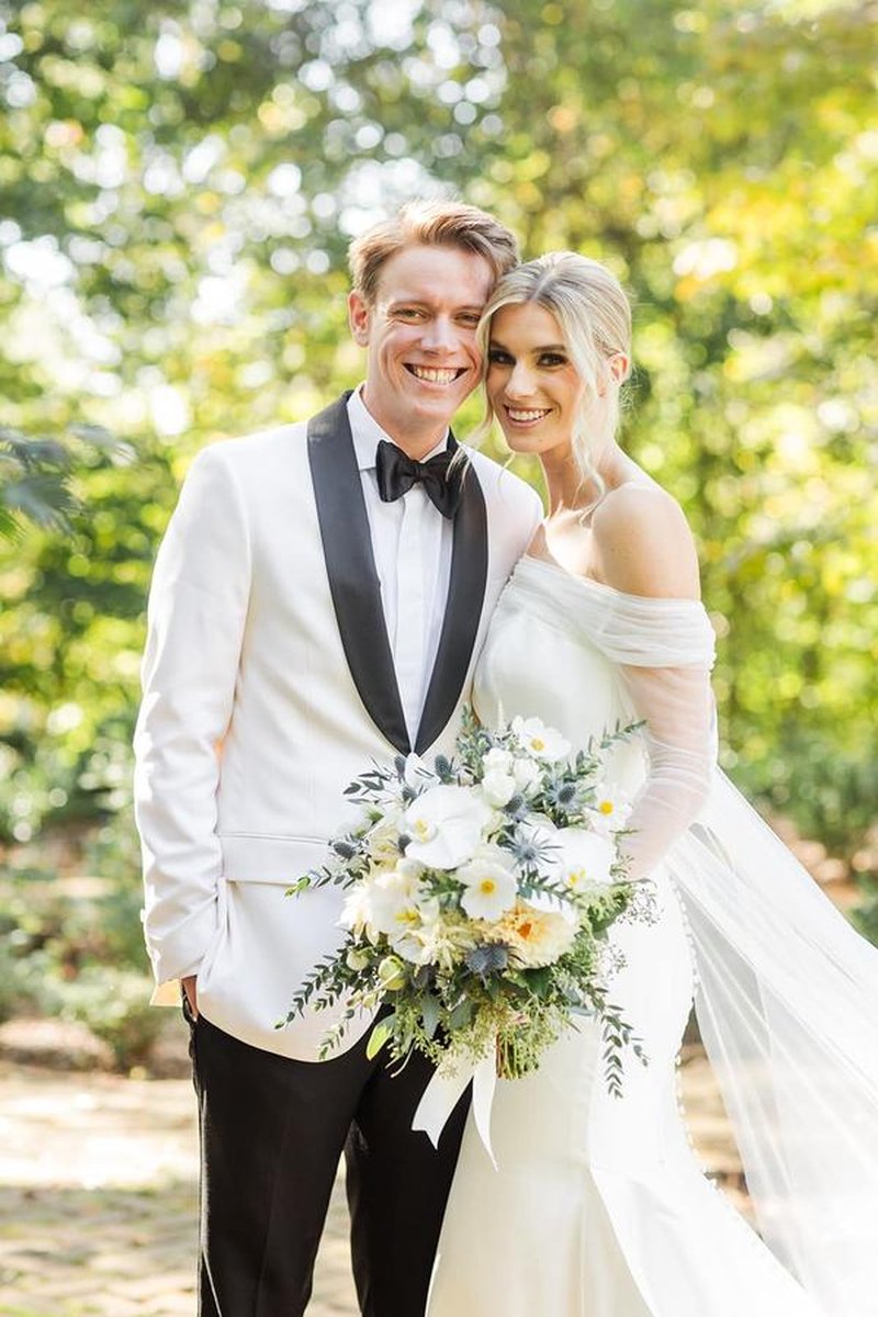 Close-up portrait of bride and groom smiling together with white floral bouquet